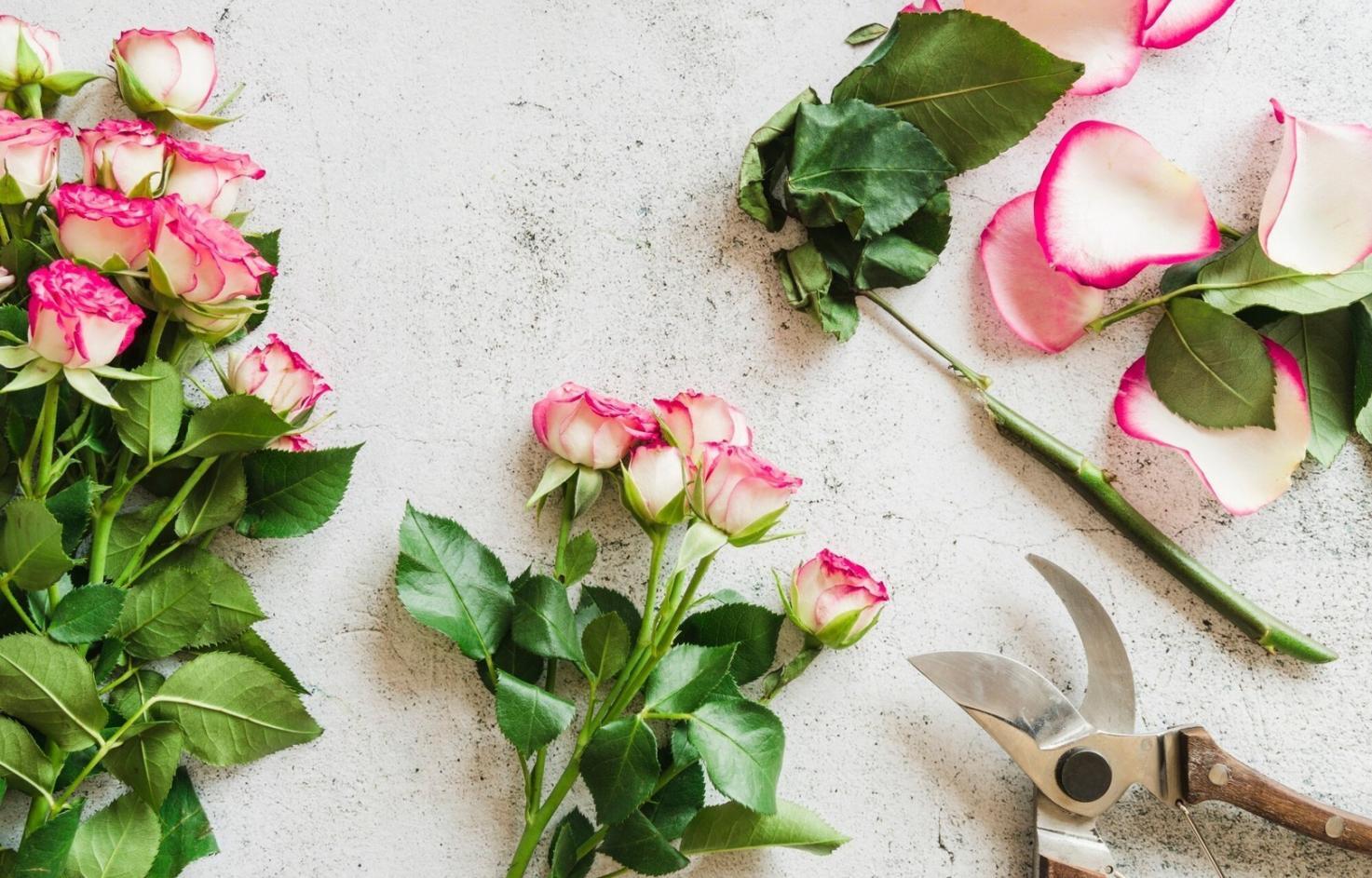 Professional flower arrangement workspace showing fresh blooms and design tools